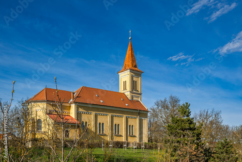 Принти на полотні Historic church building with tower and red tiled roof under blue sky