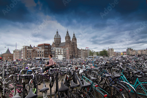 Canvas Print Massive bicycle parking near Amsterdam Centraal Station with Sint-Nicolaaskerk in the background