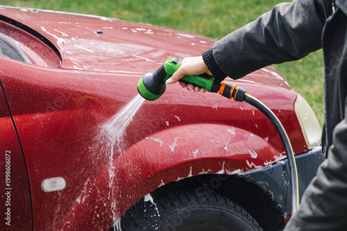 Tableau sur toile Washing red car with garden hose