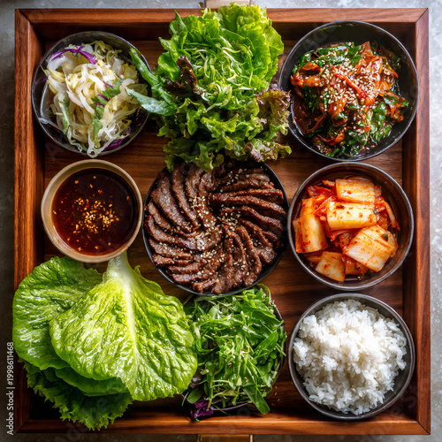 Stylized flat lay of a bulgogi dinner spread marinated beef strips arranged in a perfect spiral on a wooden tray, surrounded by lettuce leaves, ssamjang sauce, kimchi, pickled radish, and steamed rice