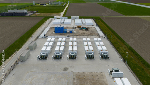Dronten, Netherlands - 04 April 2026: Aerial view of the Giga Storage battery facility at Olsterdwarspad with rows of white containers and transformers surrounded by green fields.
