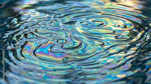 Vibrant Iridescent Oil Slick on Rippling Water Surface with Rainbow Colors and Shimmering Reflective Textures