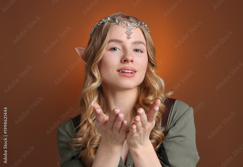 Fototapeta premium Beautiful girl dressed as elf on brown gradient background