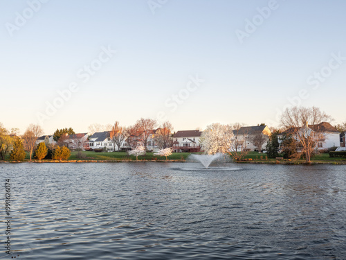 Suburban homes behind lake with water fountain in Ashburn Virginia