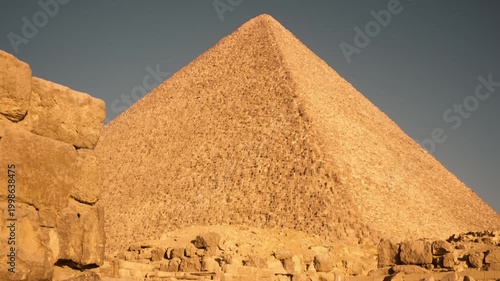 Cinematic morning approach to Great Pyramid of Khufu in Giza Egypt with golden sunlight. A smooth Steadicam shot captures a cinematic approach to the Great Pyramid of Khufu in Giza, Egypt