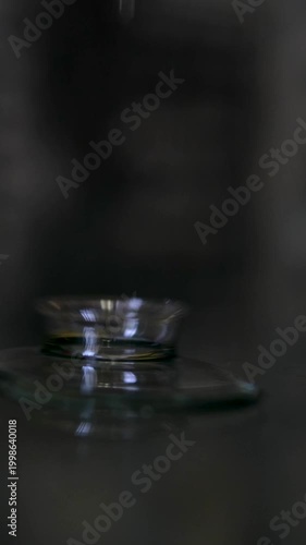 Pouring oil in thin stream on glass dark background closeup macro liquid texture