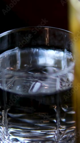 Adding ice cubes with tongs to water glass tropical juice passion fruit mango orange mint drink