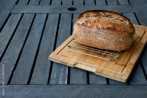 A loaf of freshly baked homemade sourdough bread on a wooden table.