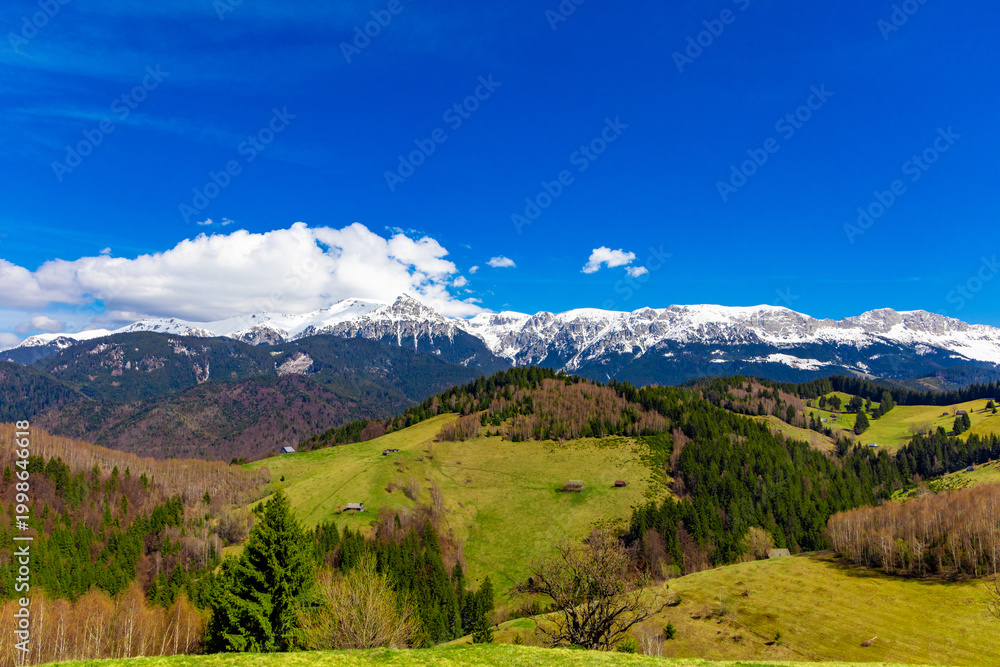Fototapeta premium Scenic view of the Carpathian Mountains in Romania, specifically showcasing the snowy peaks of the Bucegi Mountains in spring