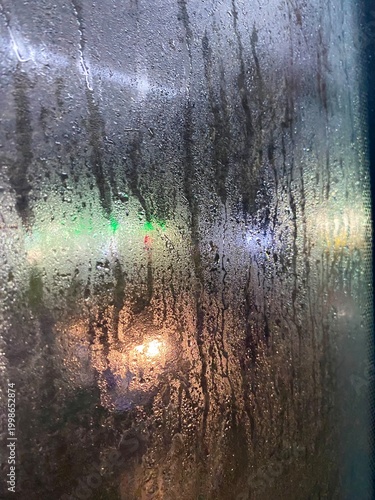 А foggy window in the rain and city lights weather season vertical photo background wallpaper vertical orientation 