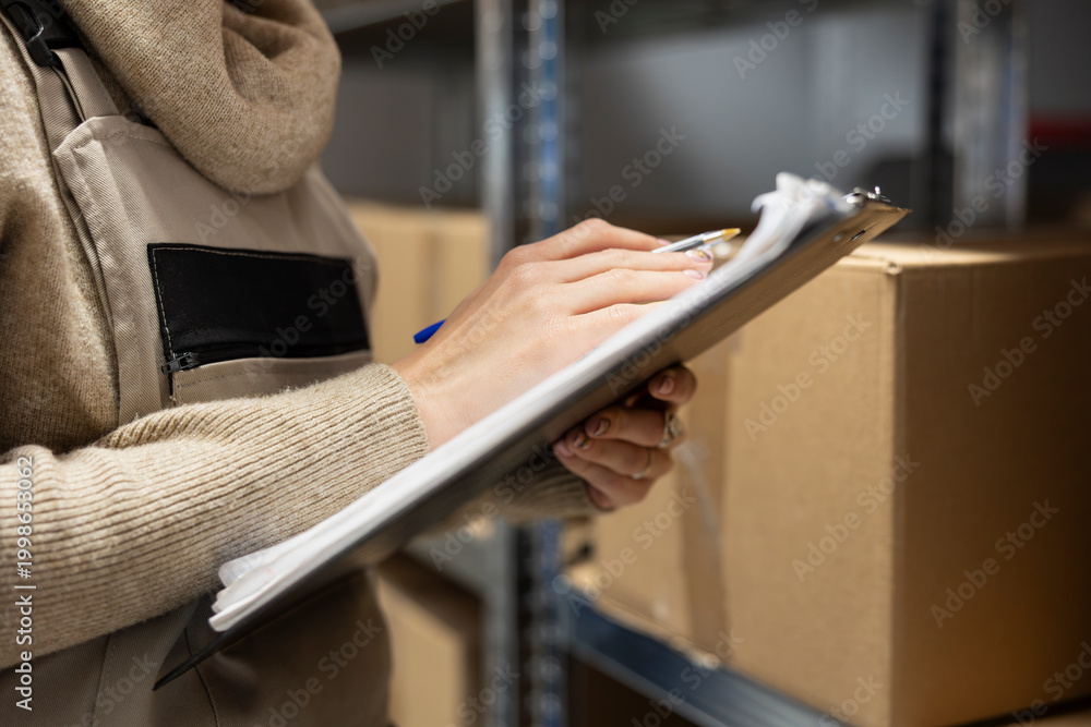 Naklejka premium Logistics worker in a depot coordinating storage and package handling, solving distribution tasks before shipment process. Warehouse interior features crates and shelving for supply chain.