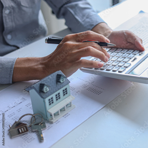 A person using calculator to determine costs of housing, such as mortgage payment, down payment or closing fees associated with property purchase.