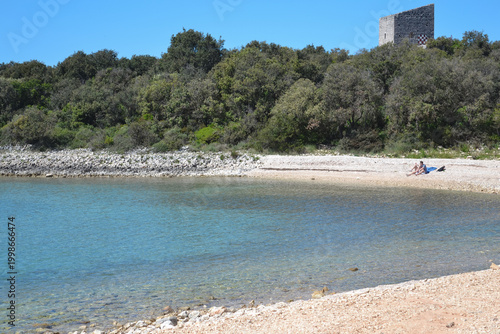 Quiet Pebble Beach in Kožino, Zadar County, Croatia with Clear Adriatic Sea and Historic Tower