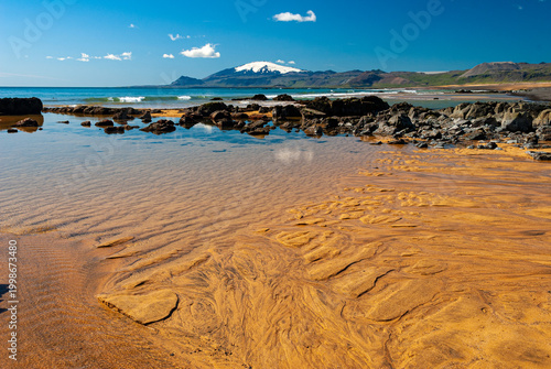 Snæfellsjökull glacier volcano seen from Iceland beach with sand patterns and ocean in foreground scenic landscape