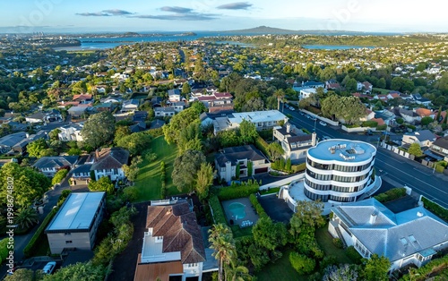 фотографія Aerial view of Remuera, Auckland, New Zealand, showcasing a residential neighborhood with lush greenery, diverse architecture, and a glimpse of the harbor and Rangitoto Island in the distance