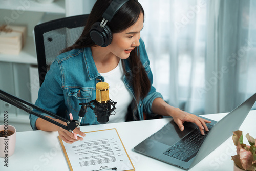 Obraz na płótnie Host channel Asian influencer talking in broadcast streaming online wearing headset on social media live with script note, greeting listeners in life coaching or marketing at modern studio