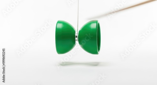 Green Yo-Yo Suspended in Mid-Air Against White Background.