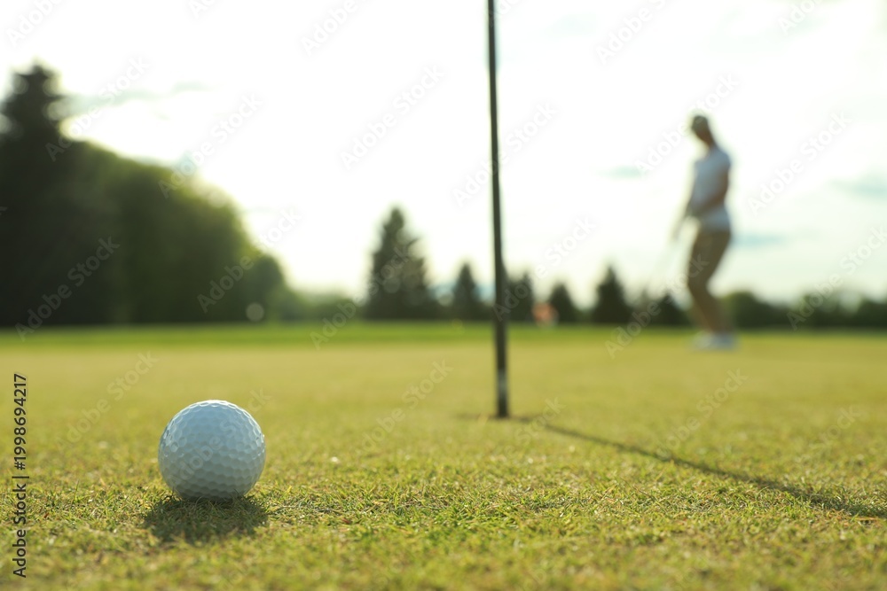 Obraz premium Woman playing golf at green course, focus on ball. Space for text