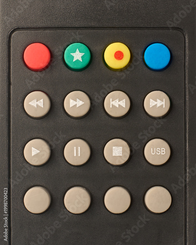 Fotografie media playback and function buttons on matte black plastic remote control, red g