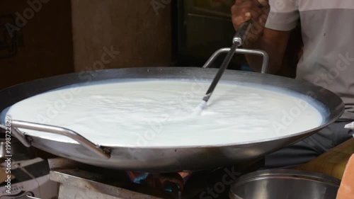 Boiling cow milk in large pot at roadside sweet shop in Varanasi India
