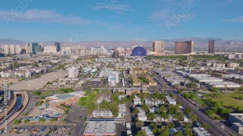 Aerial sideways dolly shot of Las Vegas suburbs and Strip skyline and mountains 