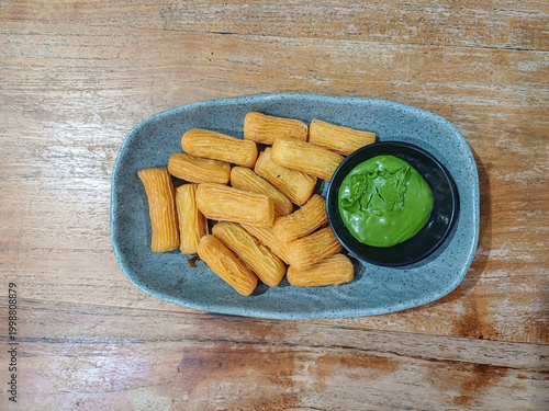 A close-up of crispy golden churros and a bowl of green matcha pasta. These sweet Spanish treats are served on a plate for a delicious culinary experience.