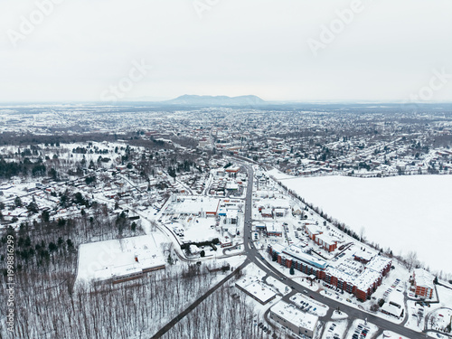 Aerial winter view of Granby city with snowy streets, church buildings and urban landscape, Quebec, Canada. g.