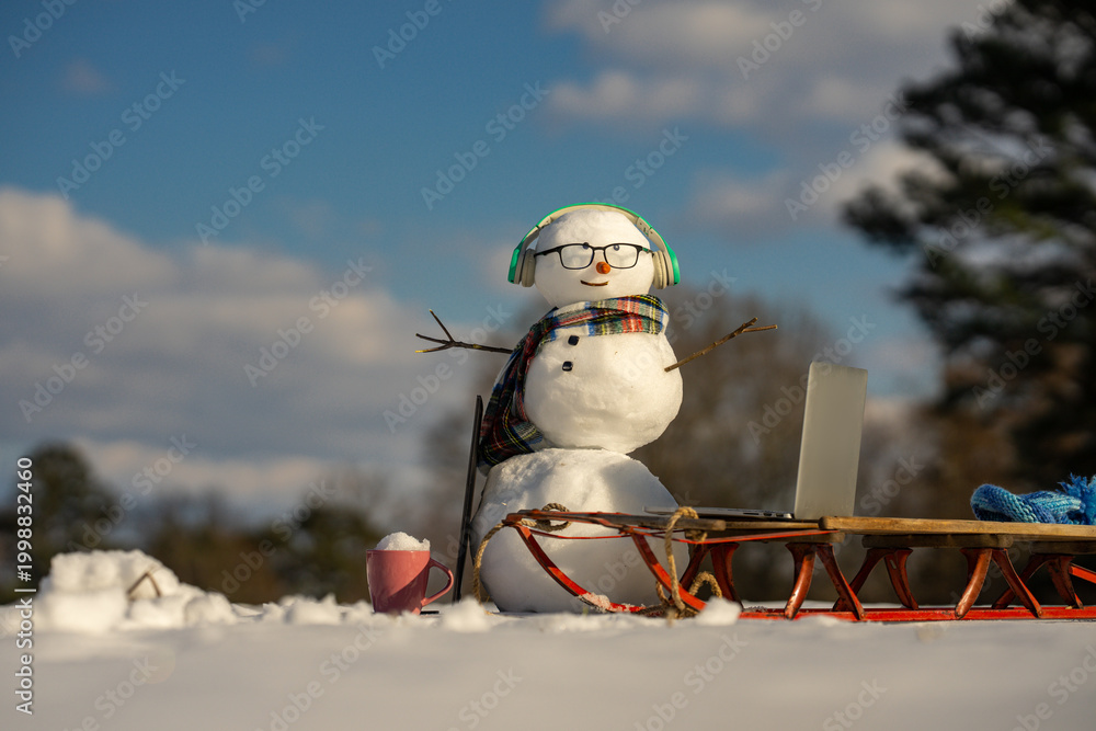 Obraz premium Snowman online freelancer scene in winter. Winter online shopping. Remote online work winter concept. Snowman freelancer with laptop in snow. Creative winter snowman with computer setup.