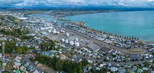 Aerial view of Napier, New Zealand, showing the city's industrial area with storage tanks, residential neighborhoods, and the coastline. 
