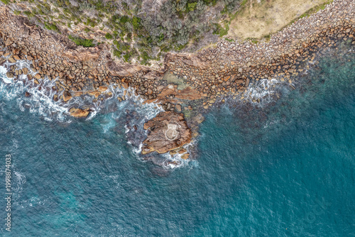 Aerial view of World War II gun emplacement at Tomaree Head in New South Wales, Australia surrounded by rugged rocky coastline and turquoise ocean water. 