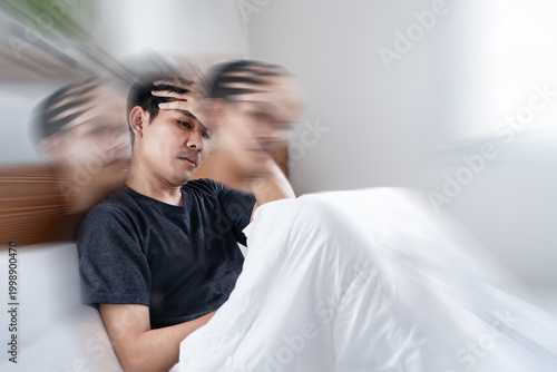 Εκτύπωση καμβά Asian man sitting on a bed feeling dizzy, suffering from a severe headache, migraine, or vertigo