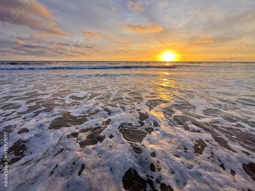 Tableau sur toile A view of the sea rushing in while the sun is halfway below the horizon at Carlsbad State Beach