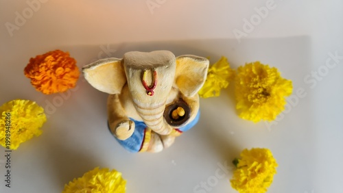 Top view Lord Ganesha idol with marigold flowers on minimal festive background