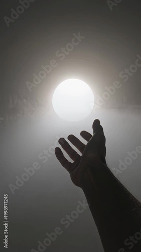 Hand reaching toward bright light in dark tunnel silhouette, vertical footage