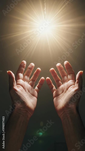 Two hands reaching up toward bright divine light from above, vertical footage