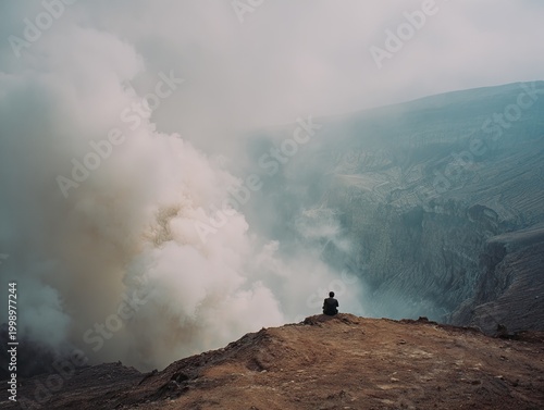 Person sitting on mountain with smoke.