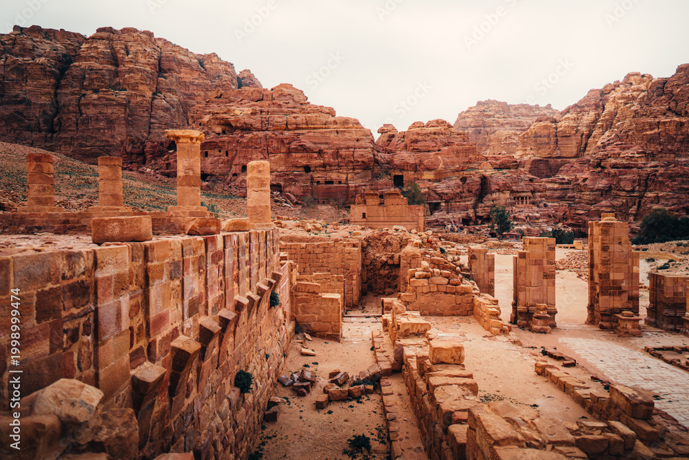 Obraz premium Ancient ruins and stone columns of the Great Temple overlooking the mountains in Petra, Jordan.