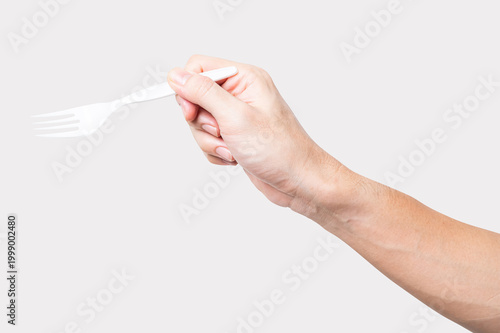 Male hand holding a white plastic fork isolated on white background with a clipping path.	