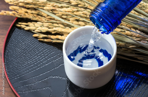 日本酒を注ぐ様子と、稲穂とぐい呑み