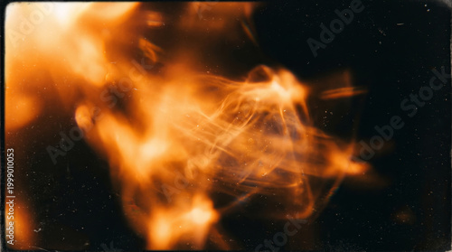 Abstract light leak glow, orange flare on dark background with blurred motion and film grain