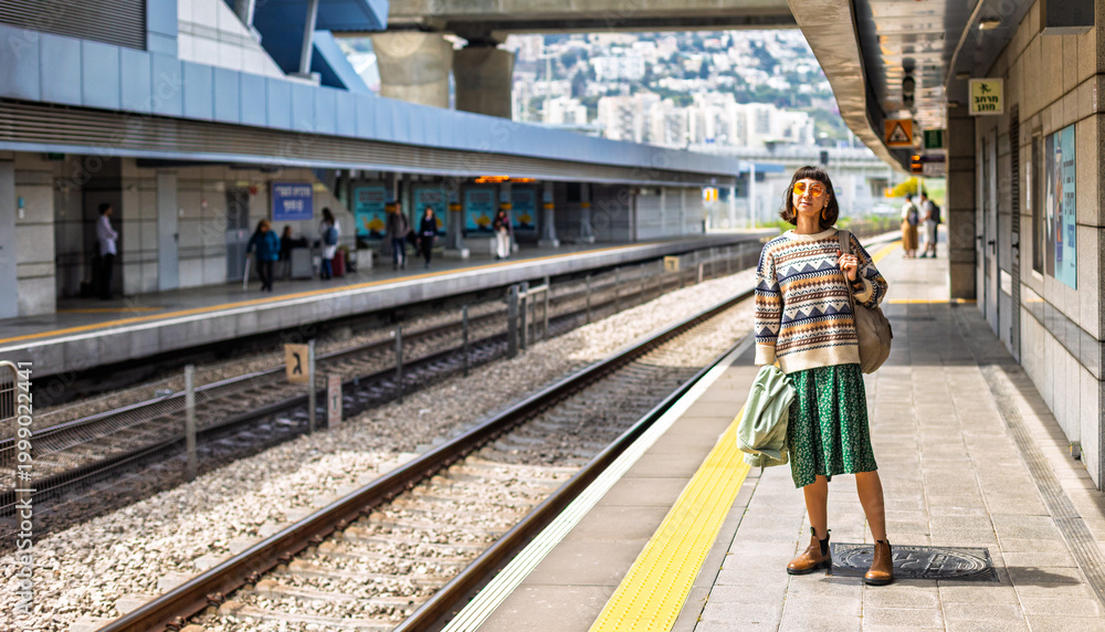 Naklejka premium girl looking at watch and waiting for train. girl standing at train station waiting for train.