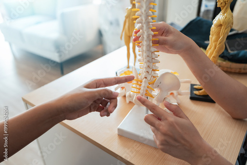 Medical healthcare diagnosis doctor patient consultation spine model examination during consultation as doctor explain spinal anatomy and pain treatment option to patient in clinic office