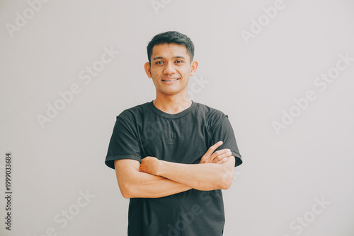 Cuadro en lienzo man with arms crossed smiling confidently against a plain light grey studio back