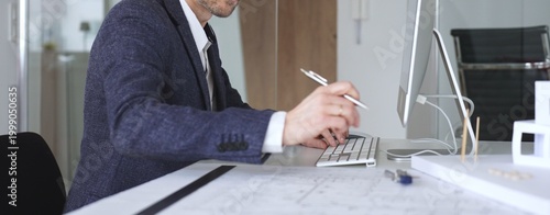 Slika na platnu Architect wearing glasses working on computer in office, typing on keyboard and designing new building projects