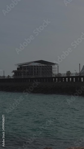 Modern building silhouette on the coast under moody grey overcast sky