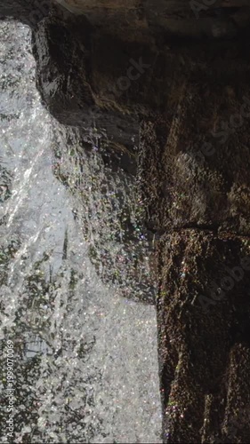 Fresh water splashing against rocky shore with drops and white foam