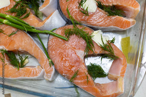 Raw salmon steaks with butter and dill. Salmon steaks in a glass baking dish. Red fish steaks.