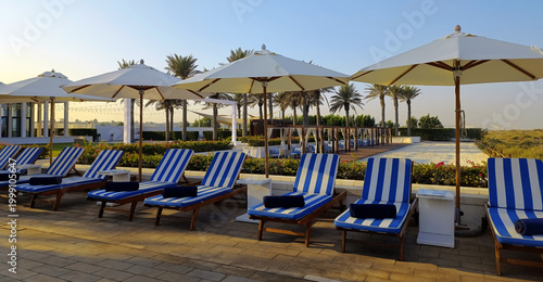 Striped sunbeds with towels and sun umbrellas by the beach on Saadiyat island in Abu Dhabi