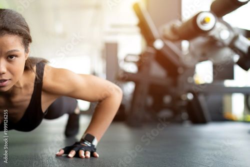 Картината върху платно Closeup of determined young Black woman doing push-ups on gym floor, intense foc