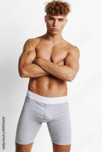 Quadro em tela Muscular man with crossed arms standing confident wearing grey underwear shorts against white background